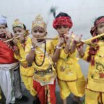 Group of young children in yellow costumes playing flutes during a festive performance with colorful headdresses and bead jewelry